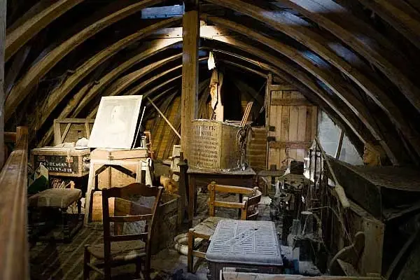 Dachboden mit Holzgebälk, alten Möbeln und Kisten vor der Dachbodenräumung